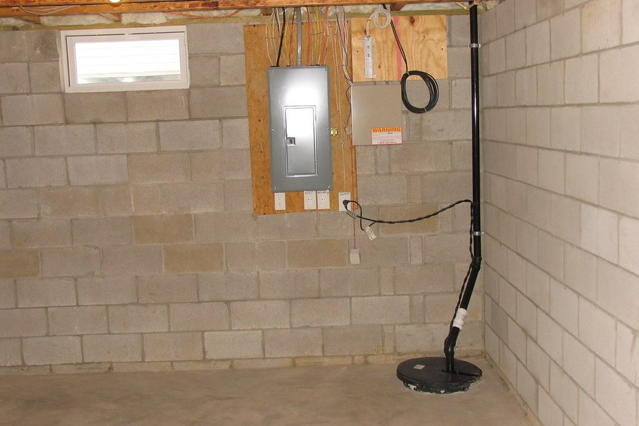 A sump pump in a concrete basement pit with rising water during heavy rainfall.