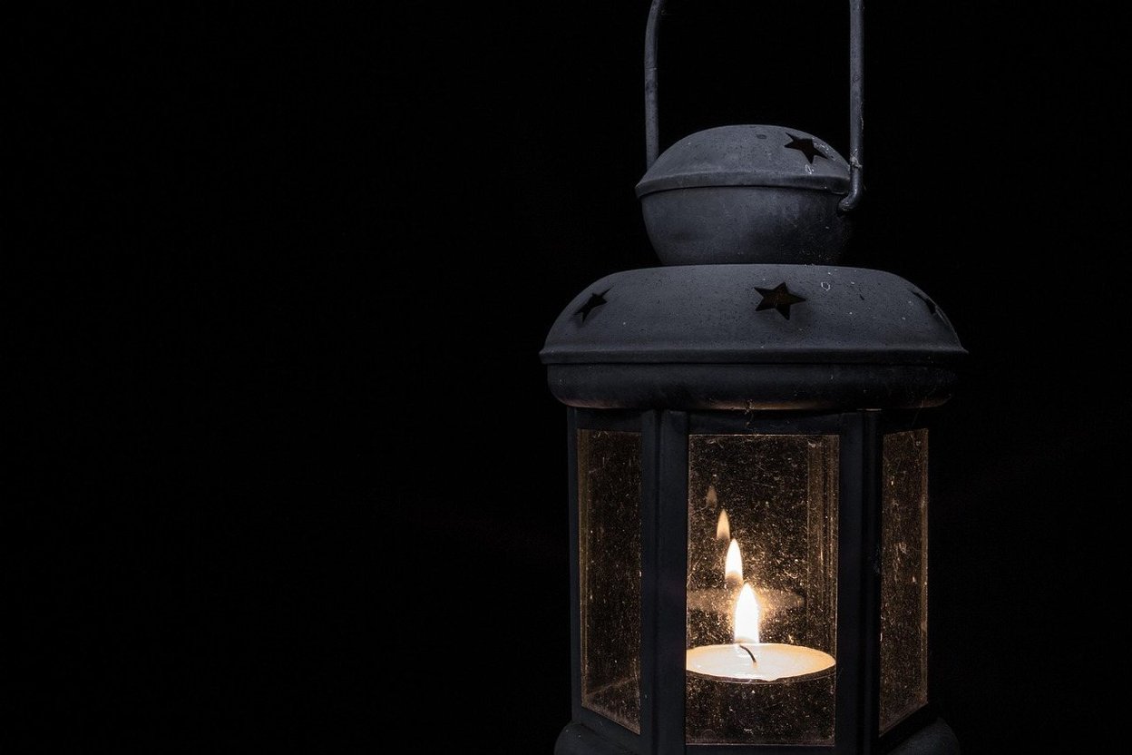 A lantern with a candle glowing in the dark