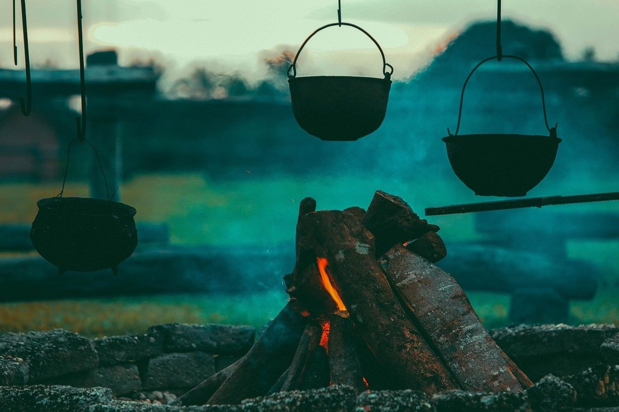 A pot hanging over a campfire outdoors