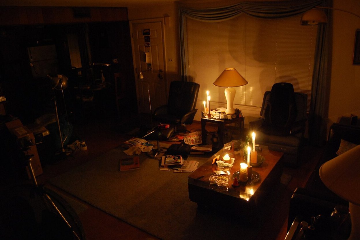 A dark living room lit by candles and a lamp during a winter power outage