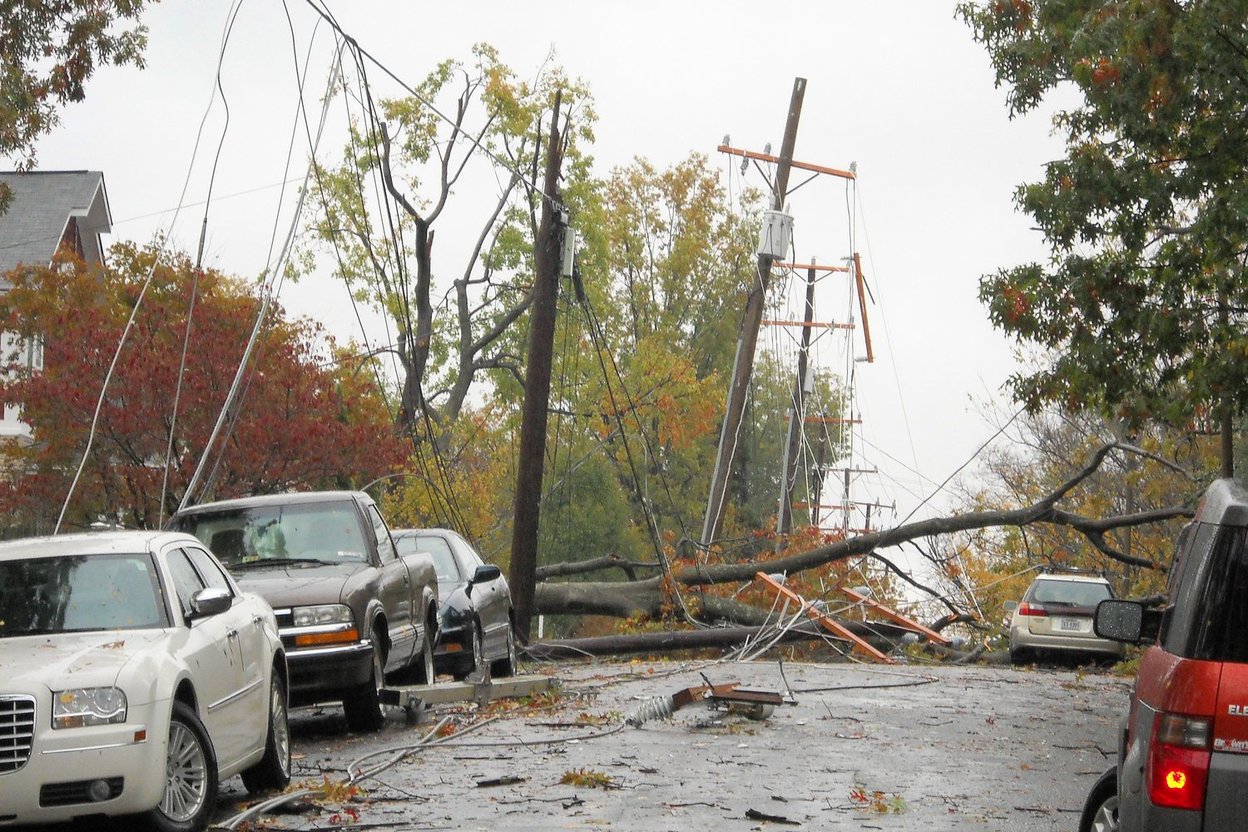 Downed power lines and broken trees across a residential street after a storm