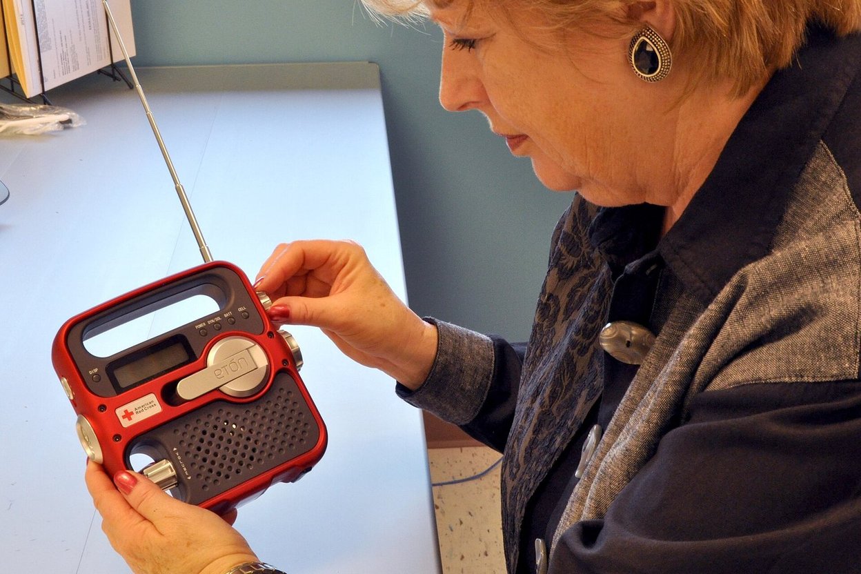 A person holding a hand-crank emergency radio